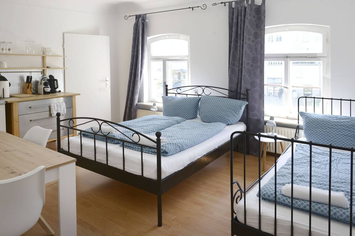 A bedroom with a bed, a desk, and a window.