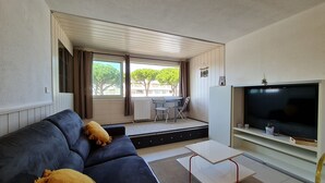 Un salon moderne avec un canapé, une table basse et un téléviseur. Il y a un balcon avec une table et des chaises.