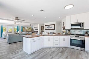 Een moderne keuken met witte kasten, een centraal eiland en een LG oven.
