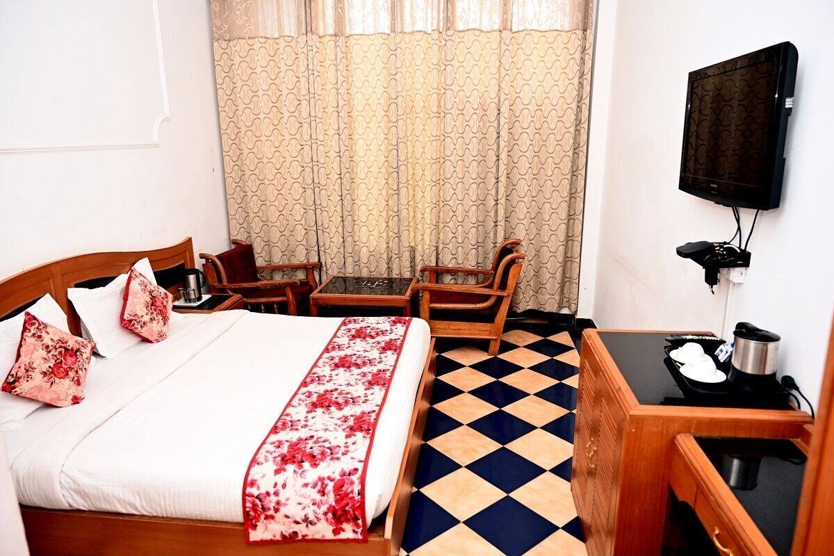 A hotel room with a bed, a desk, a chair, a television, and a window with curtains.
