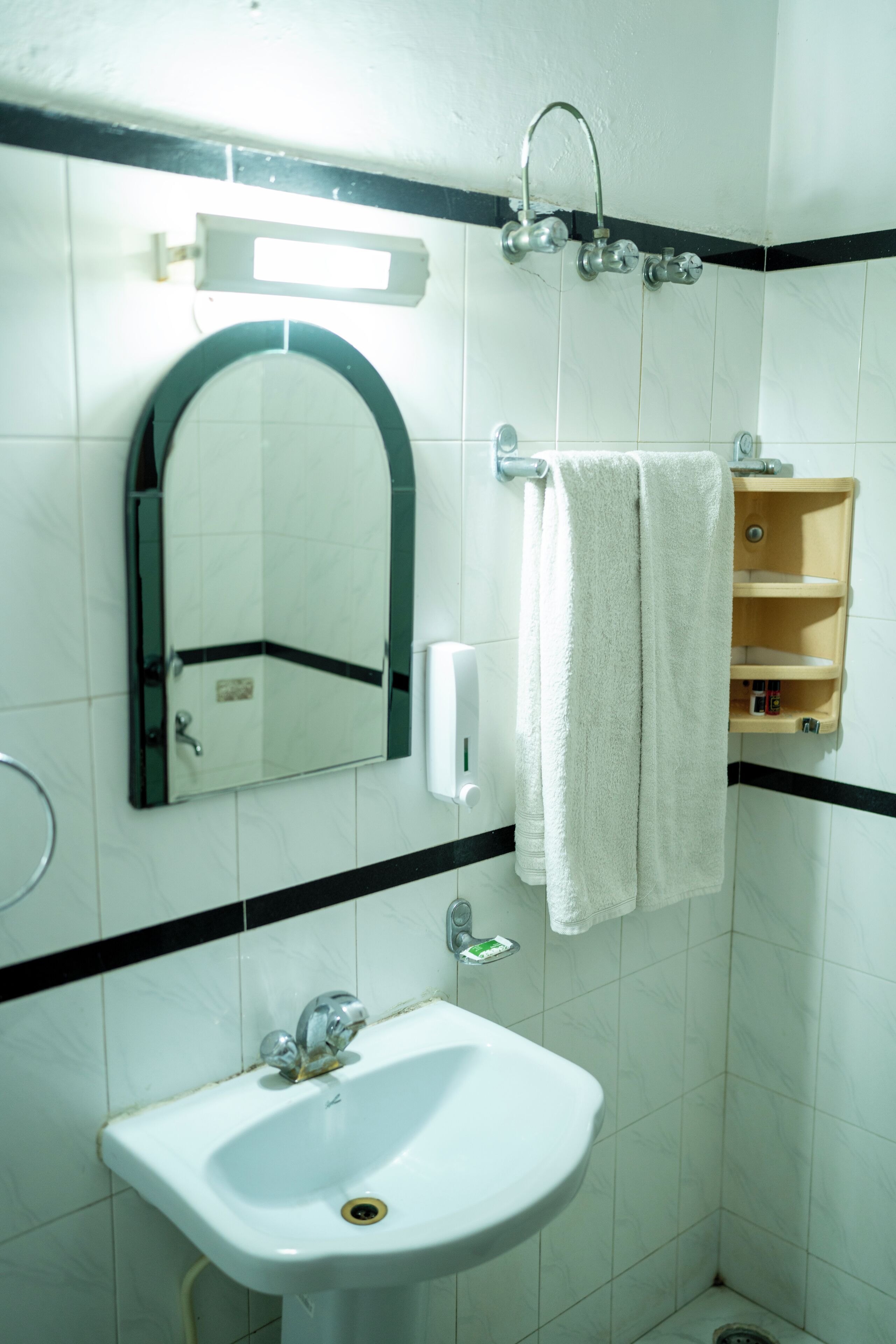 Un baño con lavamanos blanco, espejo, toallero y ducha.