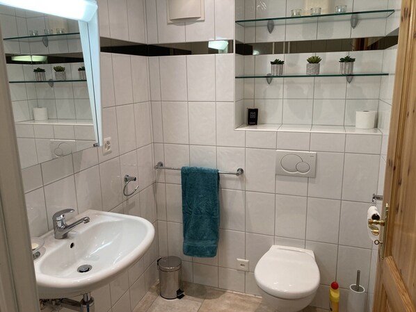 A modern bathroom with a white sink, a bidet, a glass shelf with toiletries, and a towel rack. - Nendaz, 4 bedroom apartment, 5 mins walking distance to ski lift (haute nendaz)