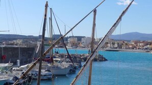 A marina with boats docked, a clear blue sky, and buildings in the background.
