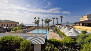 Une piscine sur le toit, bordée de palmiers, avec un ciel dégagé.