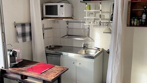 Eine kleine Küche mit Mikrowelle, Spüle und einem Esstisch mit einem Stuhl.