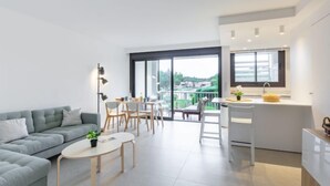 Eine moderne Wohnung mit Wohnbereich, Essbereich und Küche. Sie verfügt über ein großes Fenster mit Blick ins Freie.