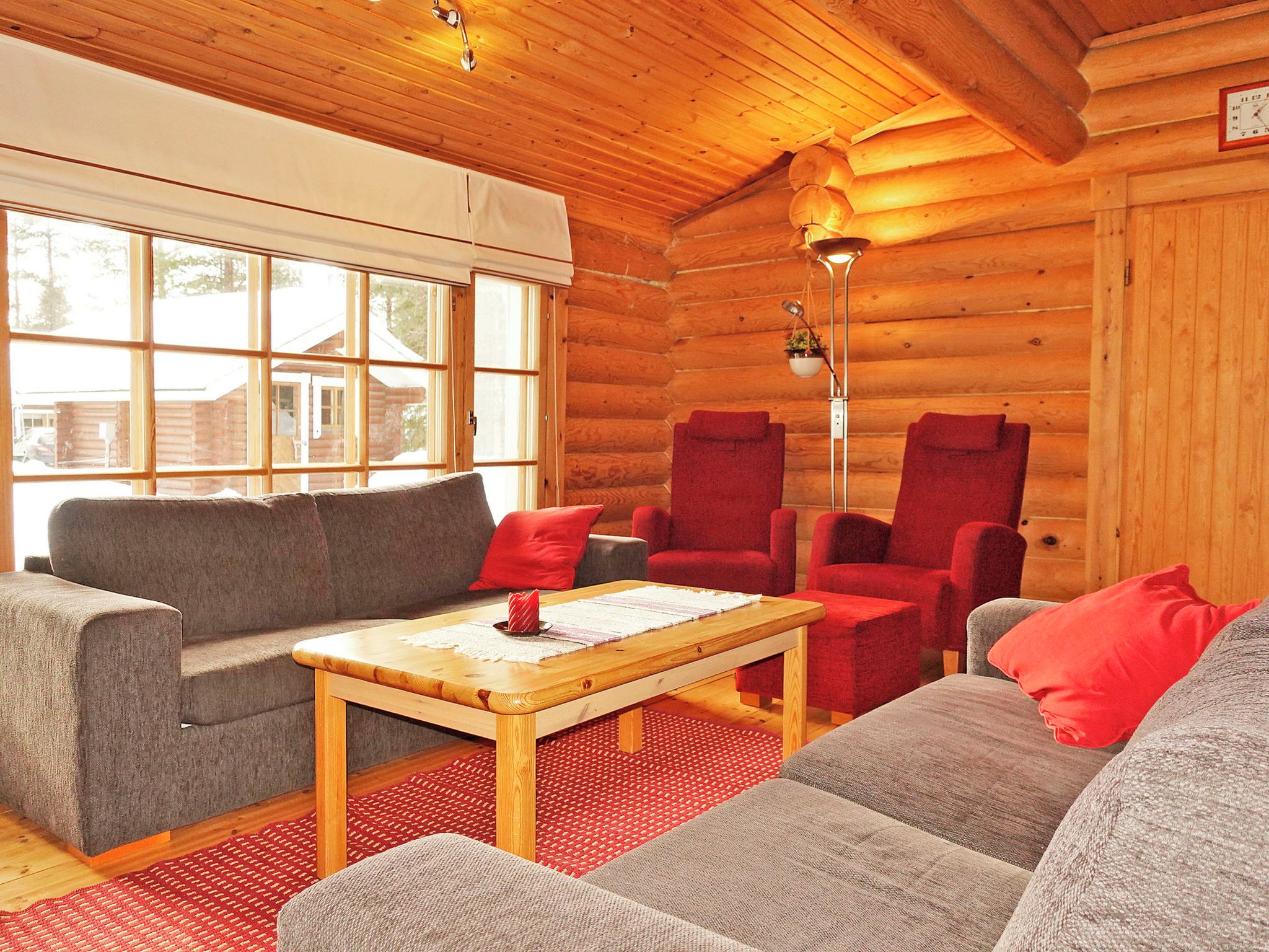 A cozy log cabin interior with a sofa, armchairs, and a coffee table.