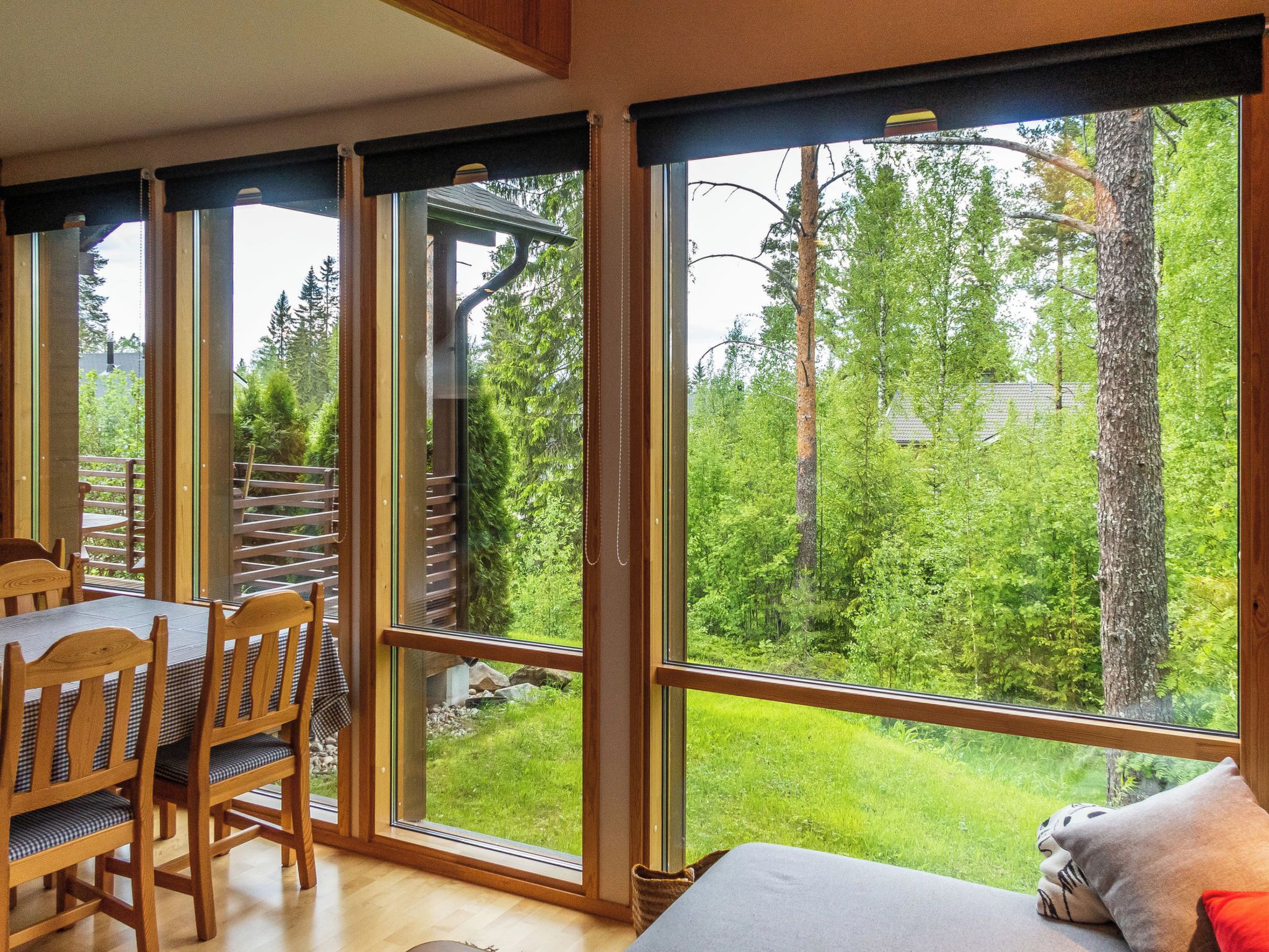 Une pièce dotée d’une grande fenêtre, d’un coin repas avec des meubles en bois et d’une vue sur une forêt.