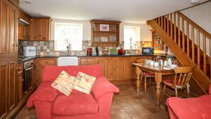 Una cocina con armarios de madera, un comedor con sofá rojo y una escalera.