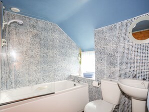 Et badeværelse med badekar, toilet og vask, alt sammen med hvide installationer.