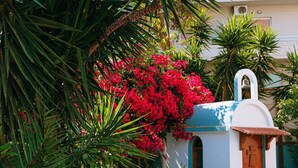 A courtyard with a white building, a blue door, and a bell tower. - Santa Marina Unique Hotel (Agios Nikolaos)
