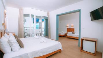 A hotel room with a large bed, a TV, a desk, and a balcony with a glass door.