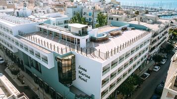 Un hotel moderno con terraza en la azotea, varios pisos y vistas al puerto deportivo.