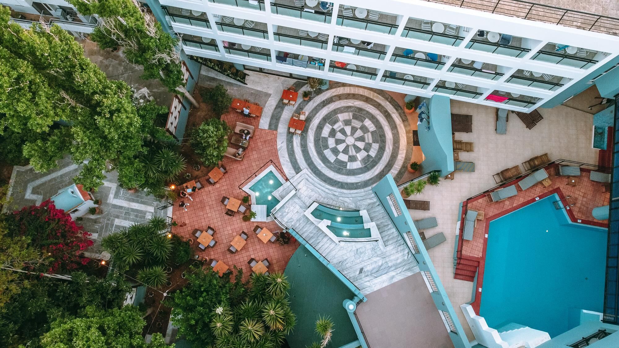 Vista aèria d'un hotel amb un pati central, piscina exterior i diverses zones de restauració.