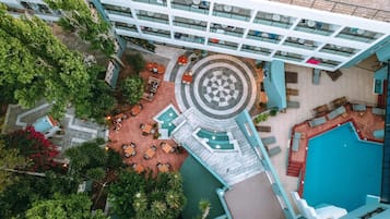 An aerial view of a hotel with a central courtyard, outdoor pool, and multiple dining areas.