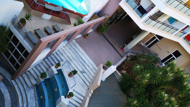A multi-level hotel with a swimming pool, outdoor seating, and a staircase leading to the upper floors. - Santa Marina Unique Hotel (Agios Nikolaos)
