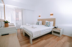 Un dormitorio moderno con cama de madera, ropa de cama blanca y una mesita de noche con lámpara y planta.