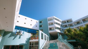 Un hôtel moderne à plusieurs étages, doté d’un escalier central et agrémenté de plantes extérieures.