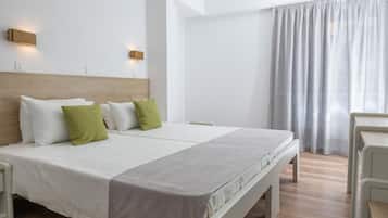 Quarto de hotel moderno com uma cama grande, duas mesas de cabeceira, um painel de cama de madeira e uma janela ampla com cortinas.