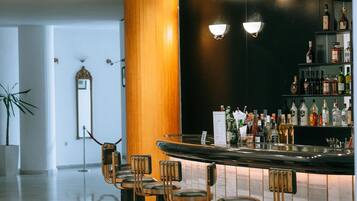 A modern bar area with a polished floor, a wooden accent wall, and a bar counter with stools.