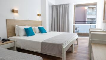 Habitación de hotel con una cama grande, mesitas de noche, un escritorio y vistas al balcón.