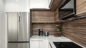 Een moderne keuken met een roestvrijstalen koelkast, witte kasten, een zwart aanrecht en een houten spatwand.