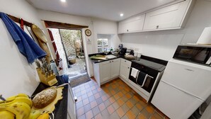 A compact kitchen with white cabinets, a stove, oven, microwave, and a sink.