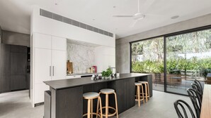 Una cocina moderna con salpicadero de mármol, una isla central con taburetes y un amplio ventanal corredera a un patio.