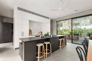 A modern kitchen with a marble backsplash, a central island with stools, and a large sliding glass door to a patio.