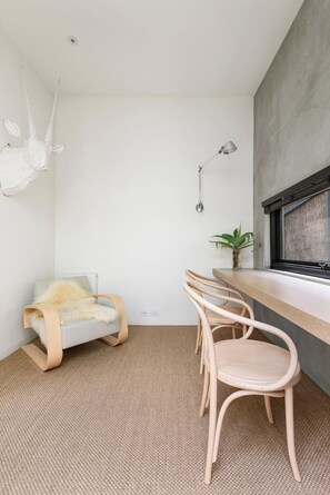 Une pièce moderne avec un canapé gris, une chaise en bois, une petite table et une lampe fixée au mur.