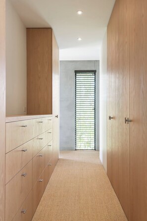 A narrow hallway with wooden cabinets and a large window with blinds.