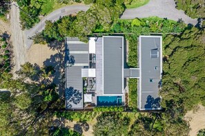 An aerial view of a modern two-story house with a large deck, a swimming pool, and a well-maintained garden. - Luxury Villas Portsea Haven (Heated Pool) (Sorrento)