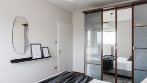 A modern bedroom with a bed, a large mirror, and a wardrobe with glass doors. - Alluring 2BR Apartment in Marousi (Marousi)