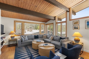 A modern living room with a sectional sofa, round coffee tables, and a TV on a stand.