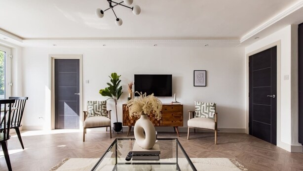 A modern living room with a glass coffee table, a sofa, a TV, and a wooden cabinet. - The Battersea Flat - Exquisite 2bdr Flat With Terrace (London)