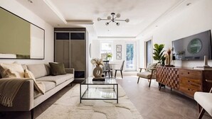 A modern living room with a sofa, coffee table, and a TV on a wooden cabinet. - The Battersea Flat - Exquisite 2bdr Flat With Terrace (London)