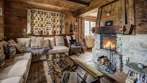 Interior acogedor de una cabaña de troncos con chimenea de piedra, paredes de madera y un espacio de estar confortable.