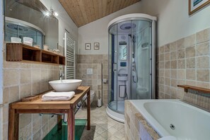 Une salle de bain moderne dotée d’une douche à parois de verre, d’une baignoire sur pieds et d’un meuble-lavabo en bois, avec un grand évier et des étagères.