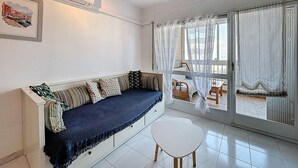 A room with a sofa, a small table, and a window with curtains.
