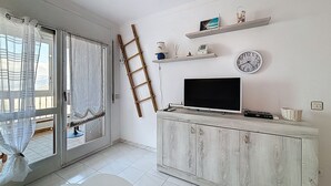 A living room with a TV, wooden cabinet, and shelves with decorative items.