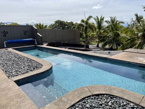 Una piscina con borde de piedra y zona de cubierta de madera.