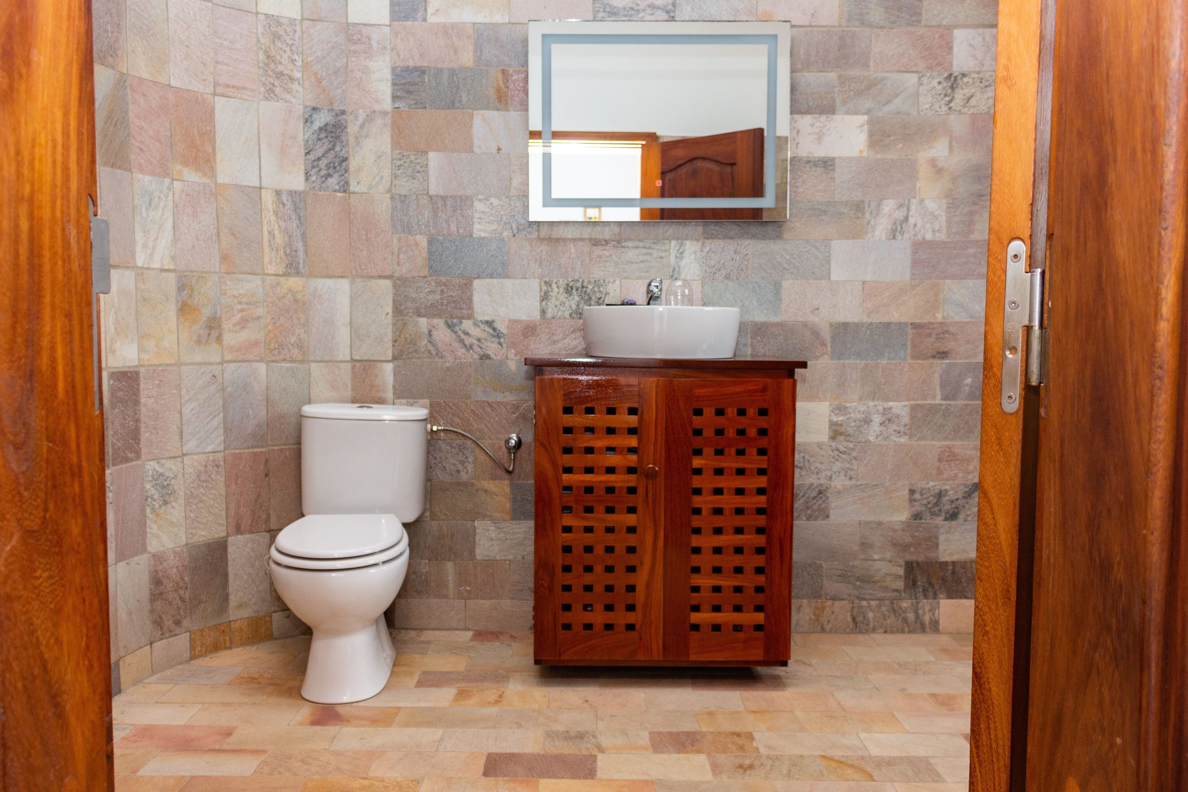 A bathroom with a toilet, sink, and wooden cabinet.