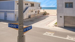 A street view with a beach in the background, a sign for Seashore or 51st Street, and a building with a garage door. - 4 Bedroom Home Steps to the Sand in Newport Beach (Newport Beach)
