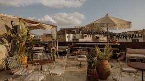 A rooftop terrace with outdoor seating, potted plants, and a view of the cityscape. - Mona Athens. (Athens)