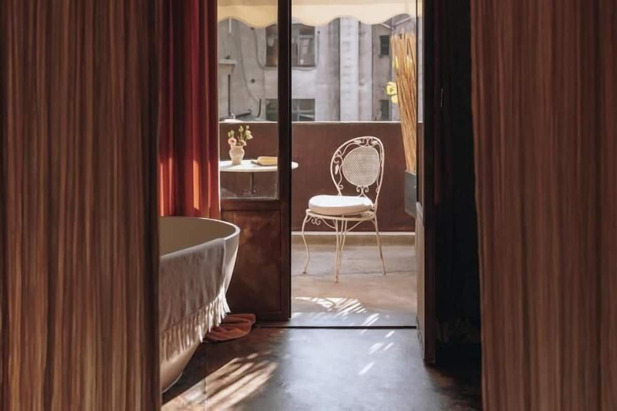 Ein Zimmer mit einer Badewanne, einem Sessel und Blick ins Freie.