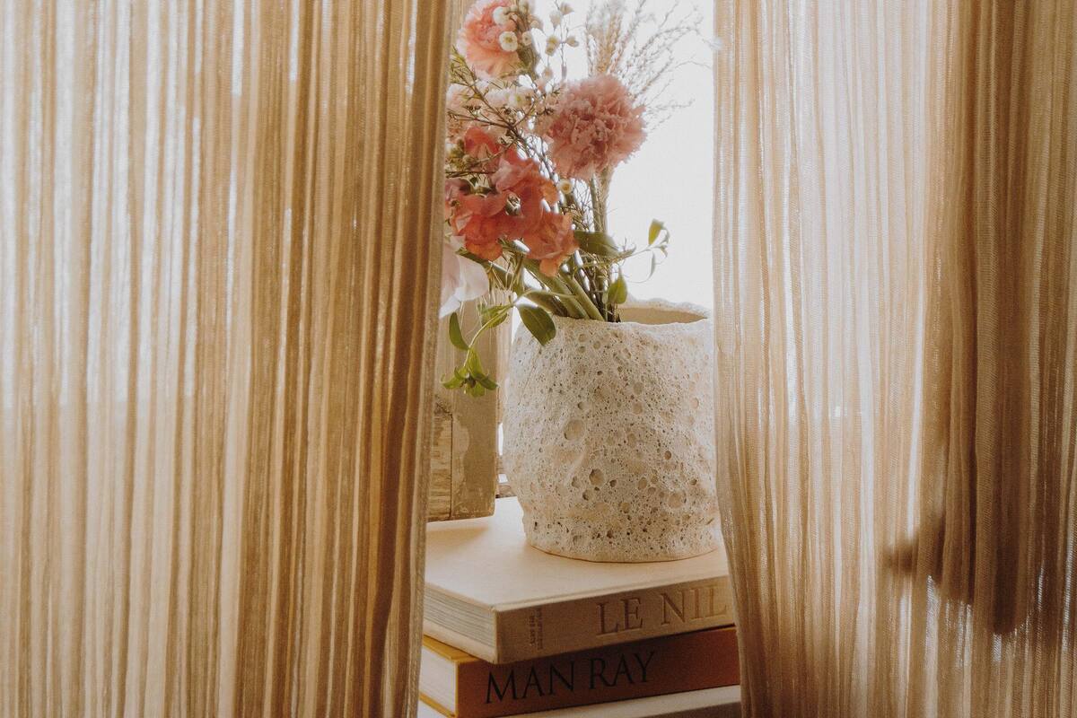 Eine weiße Vase mit Blumen auf einem Bücherstapel.