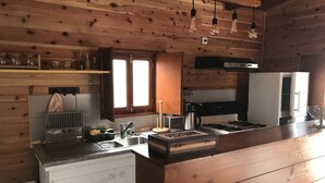 Una cocina con paredes de madera, una estufa, un lavamanos y bombillas colgantes.