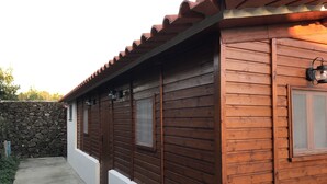 Un edificio de madera con techo de tejas, pared de piedra y sendero de concreto.