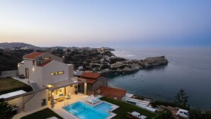 Una casa moderna con piscina, un patio y vista al mar.