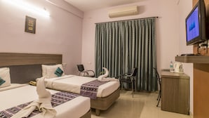 A hotel room with two beds, a desk, a chair, a television, and an air conditioning unit. - Utsav Resort by The Citi Residenci (Durgapur)